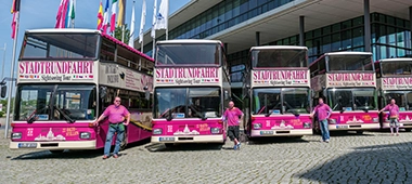 Vier Busse der Roten Doppeldecker Dresden stehen vor der Semperoper Dresden.