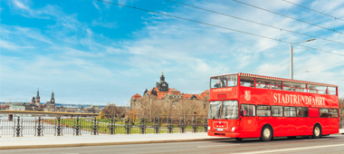 Roter Doppeldecker Bus fährt bei der Stadtrundfahrt in Dresden über die Albertbrücke in Dresden.