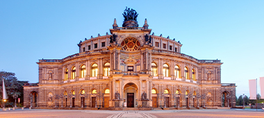 Gäste der Stadtrundfahrt fotografieren sich am Roten Doppeldecker vor der Semperoper Dresden.